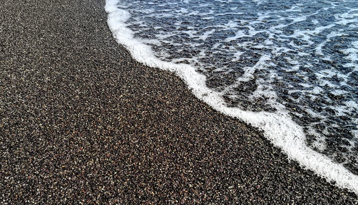 Santorini black sand beach with gentle sea wave