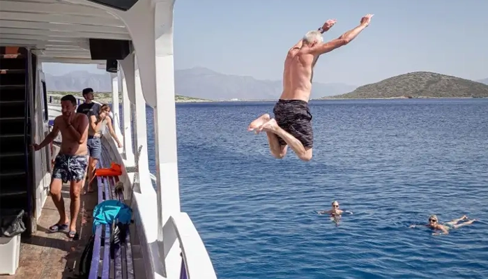 Tourist jumping from boat into the sea during Spinalonga BBQ tour in Crete with Car and Travel