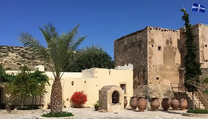 Odigitria Monastery Greek flag and palm tree in Crete during Matala Odigitria excursion with Car and Travel